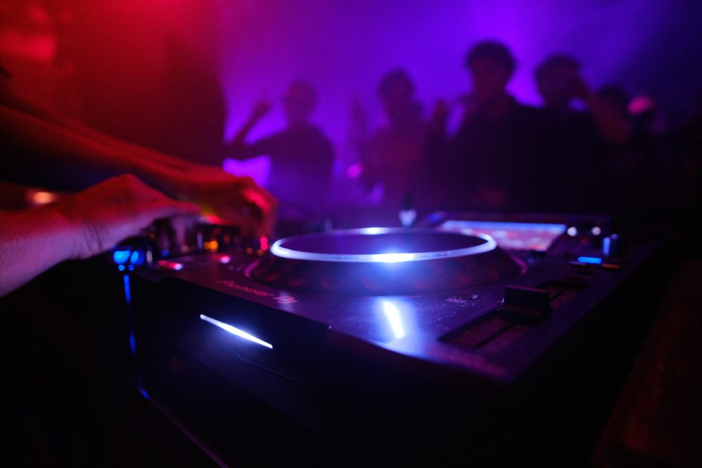 closeup shot of dj's equipment and the people dancing in the club